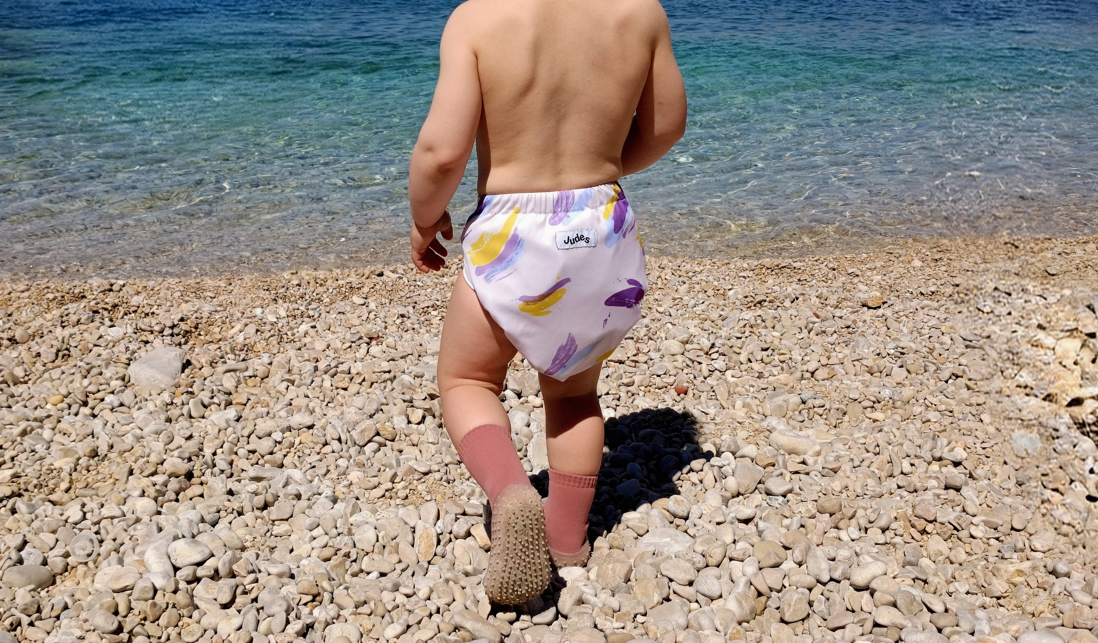 Baby mit Stoffwindel im Urlaub am Strand